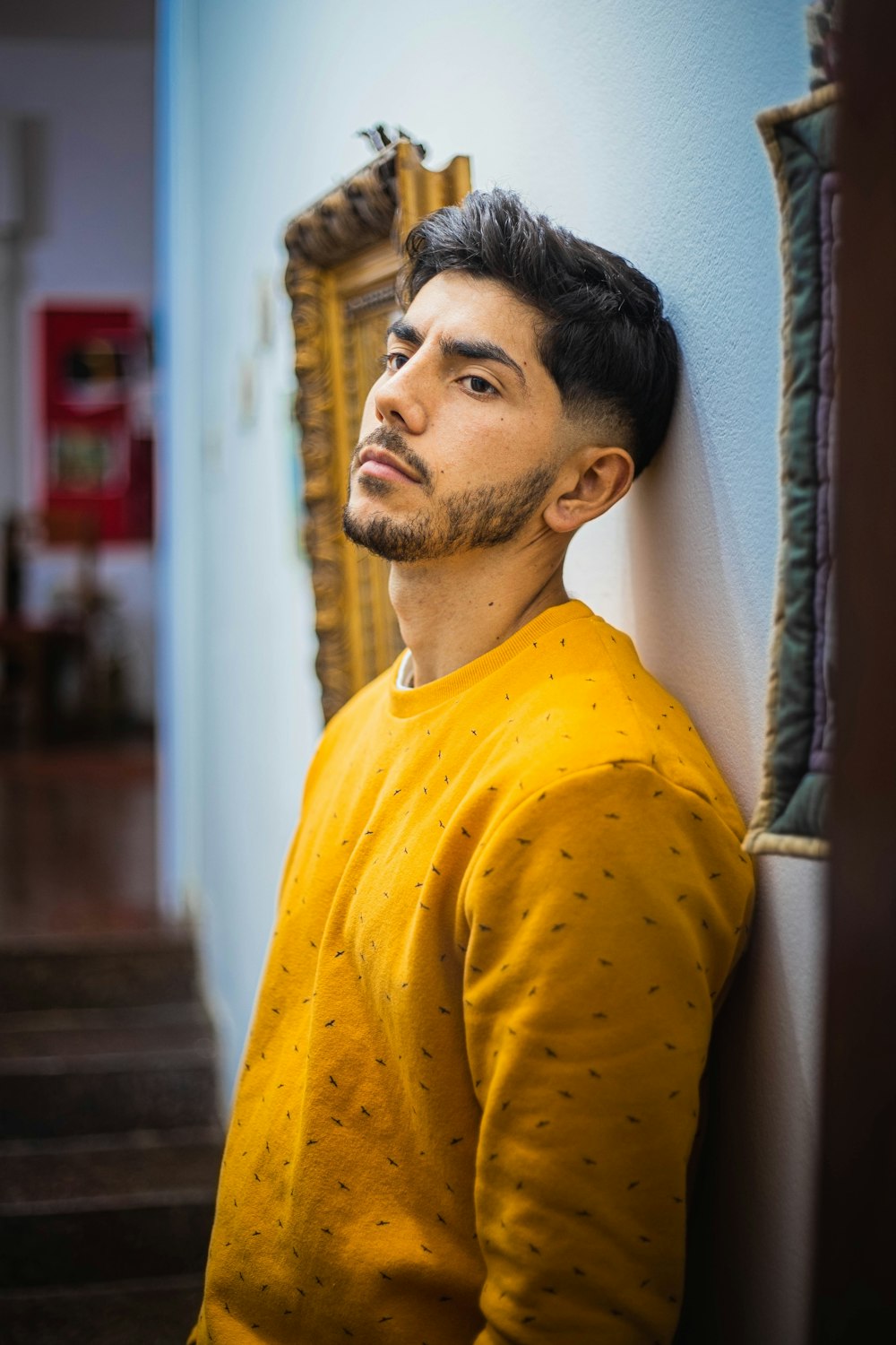 man in yellow crew neck shirt standing near white curtain