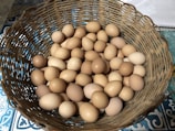Close-up of a basket filled with clean, white eggs on a rustic wooden table.