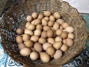 A basket filled with fresh white and brown eggs resting on a rustic wooden table.