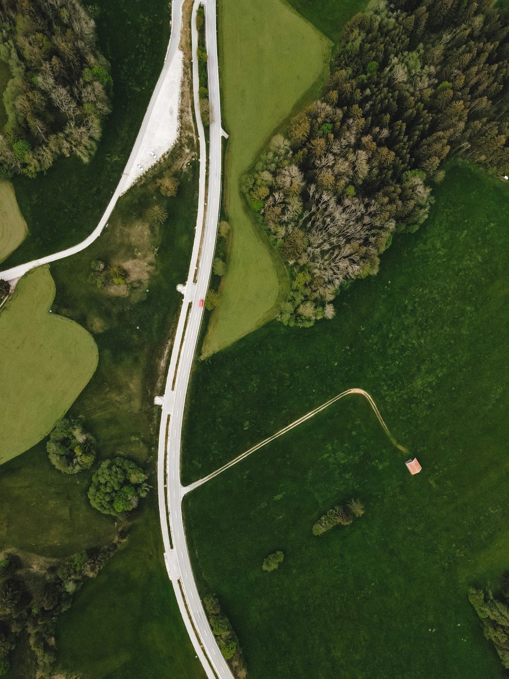 aerial view of white road in the middle of green grass field