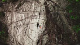 person climbing on brown rocky mountain during daytime