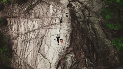 person climbing on brown rocky mountain during daytime