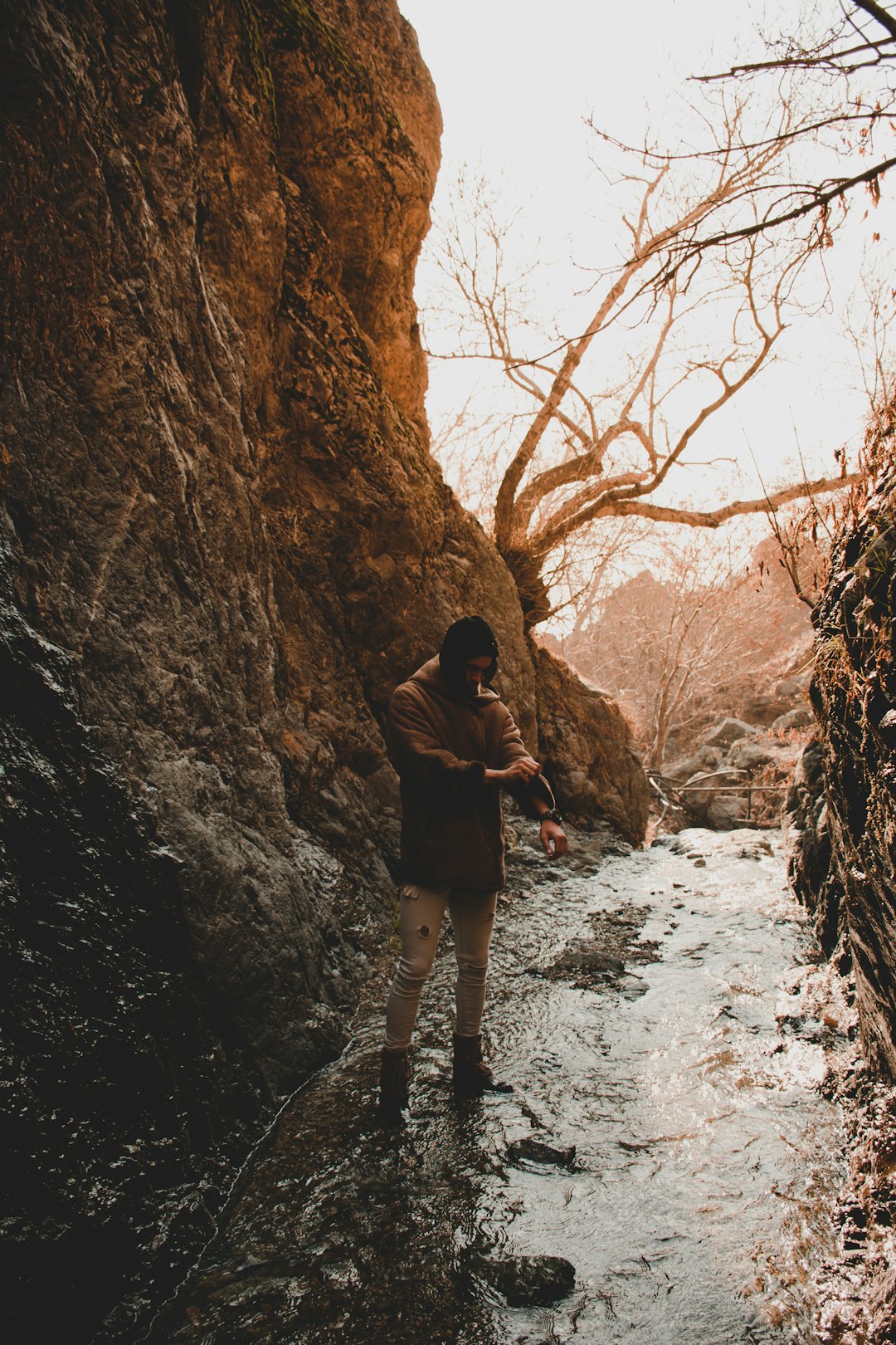 woman in black jacket and black pants standing on rocky road