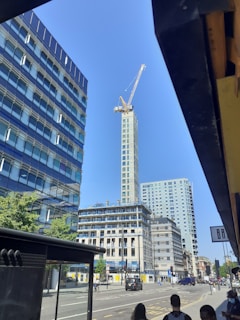 A panoramic view of a towering skyscraper under construction with cranes and workers in Qatar.
