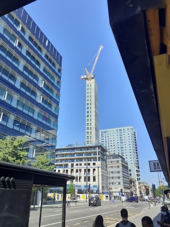 A panoramic view of a towering skyscraper under construction with cranes and workers in Qatar.