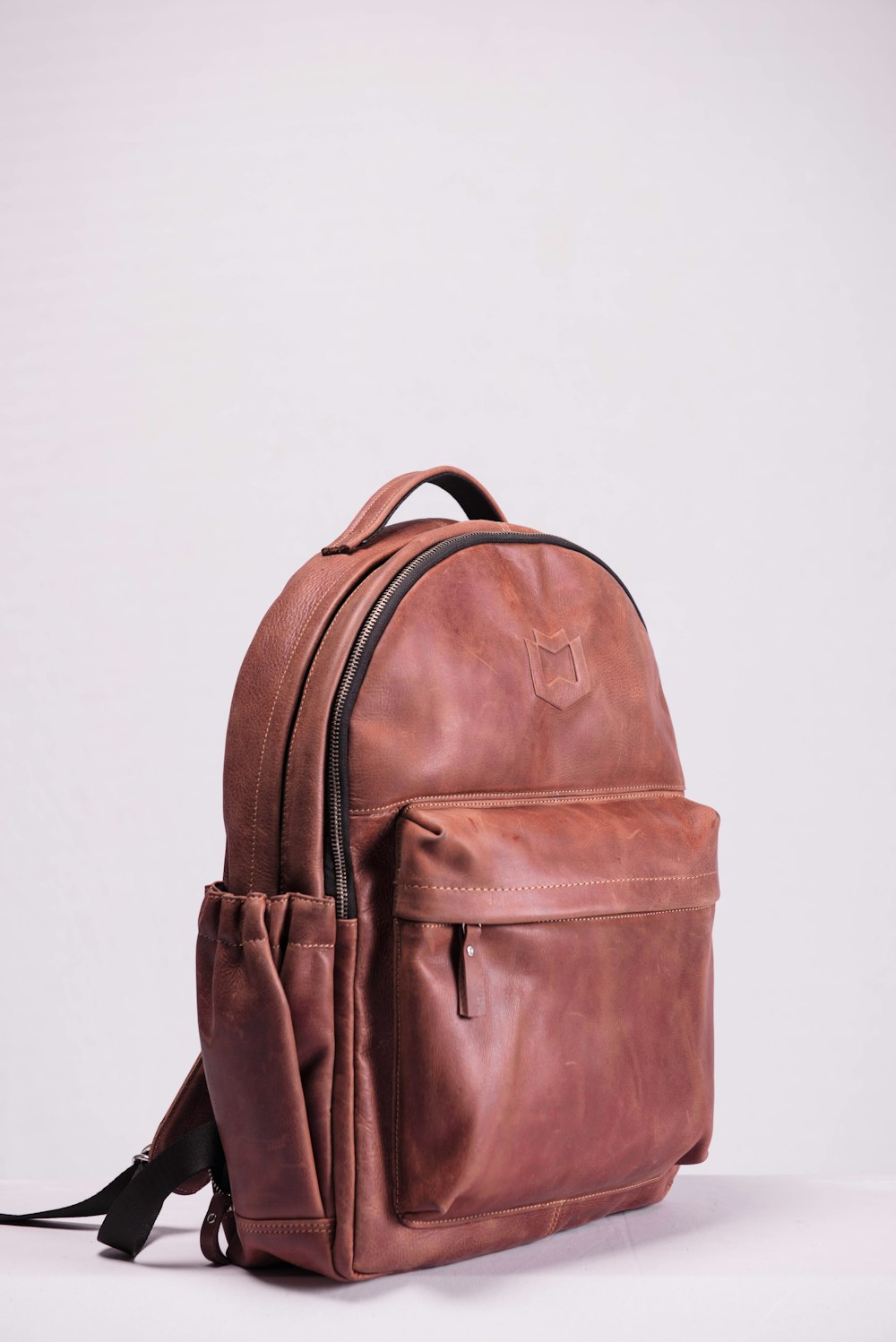 brown leather backpack on white wall