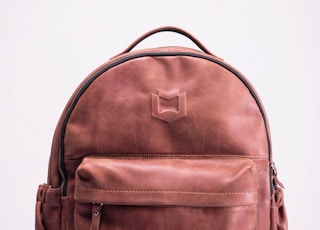 brown leather backpack on white surface