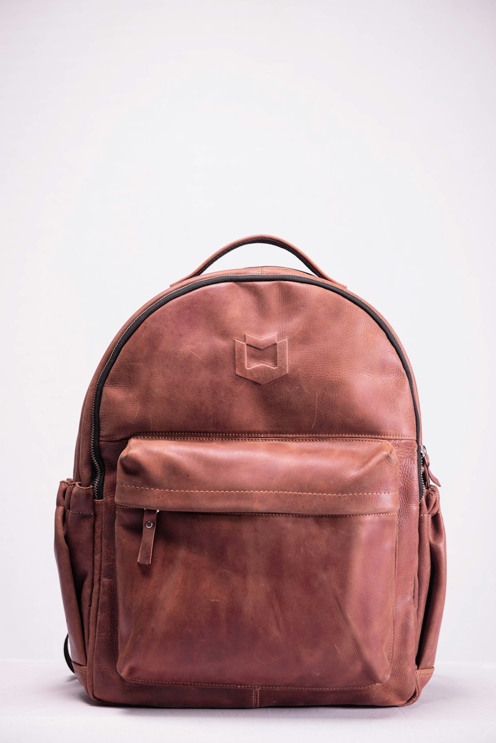 brown leather backpack on white surface