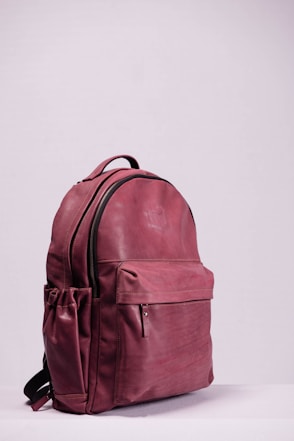 red leather backpack on white wall
