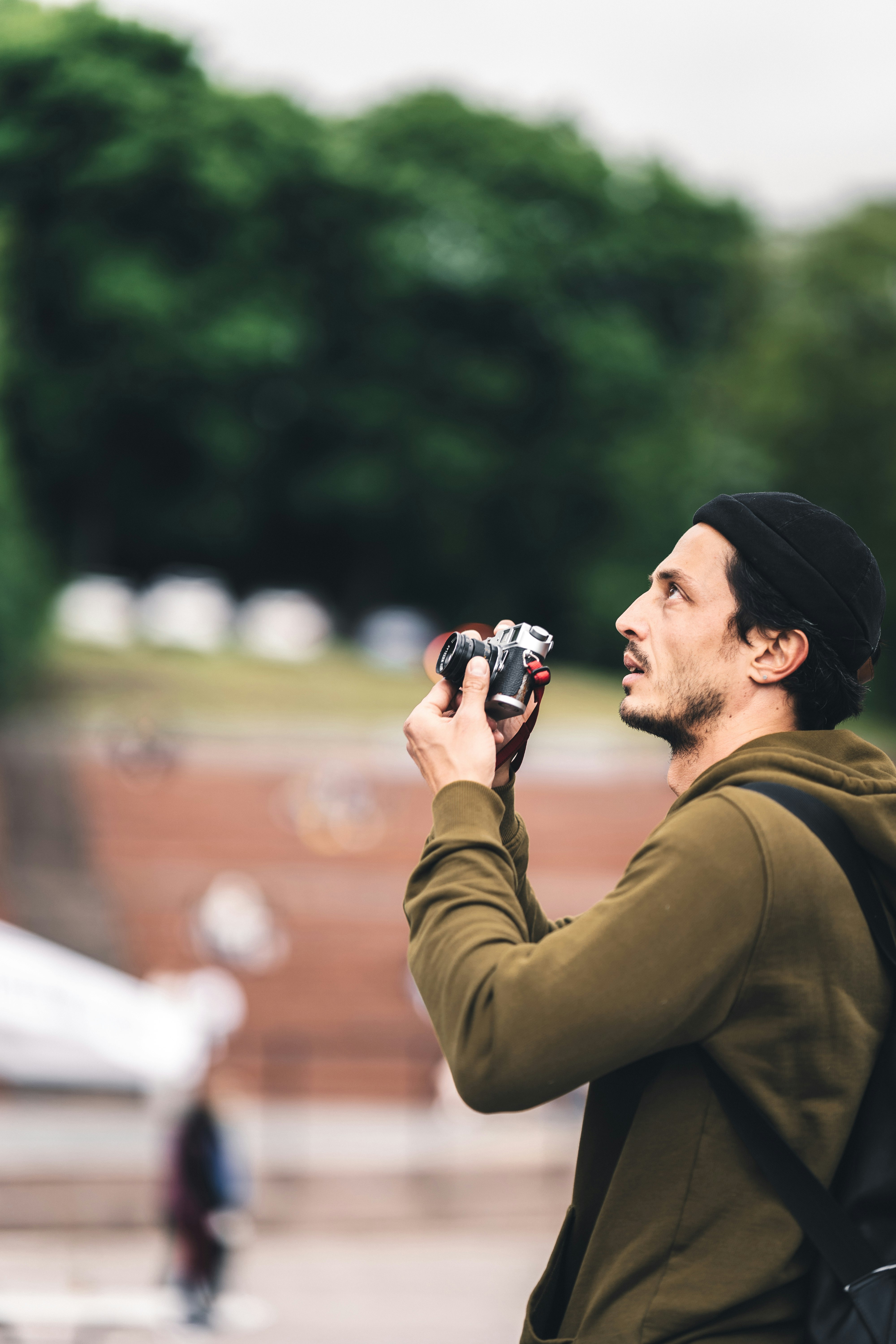 man in green long sleeve shirt holding black and silver camera during daytime