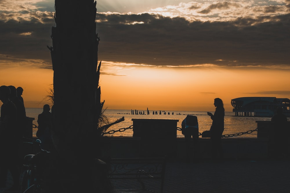 Silhouette von Menschen, die bei Sonnenuntergang am Strand stehen