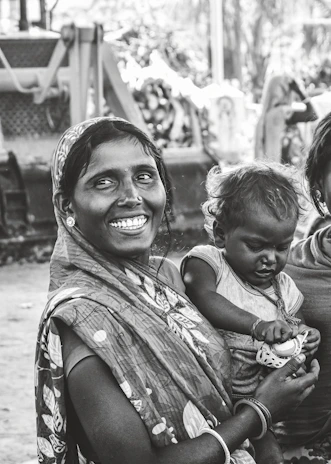 Indian nurse assisting a mother and child during a free medical camp outdoors.