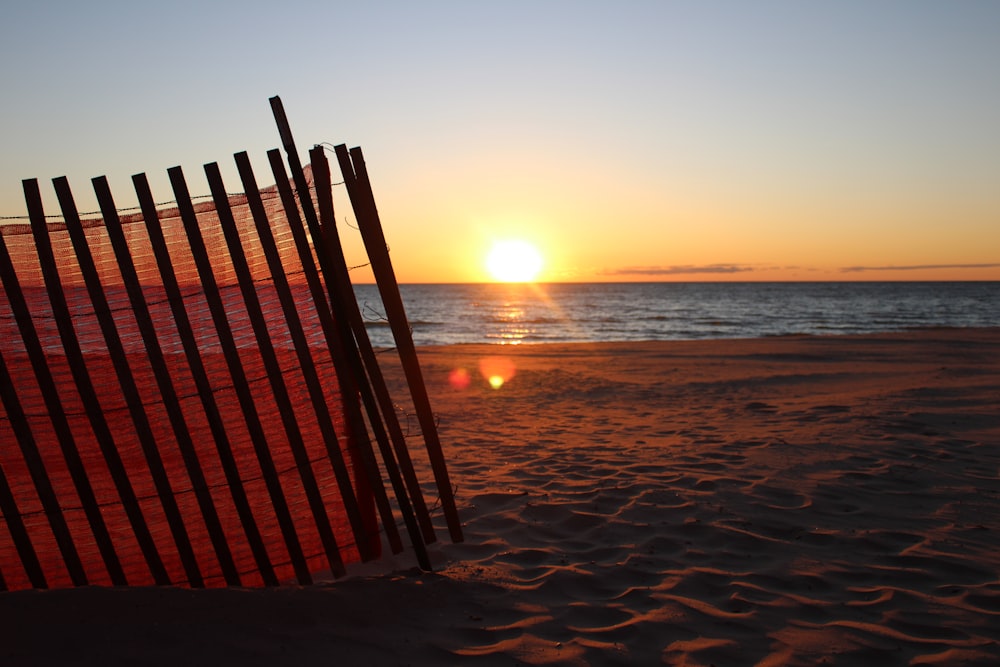 cerca de madeira marrom na praia durante o pôr do sol