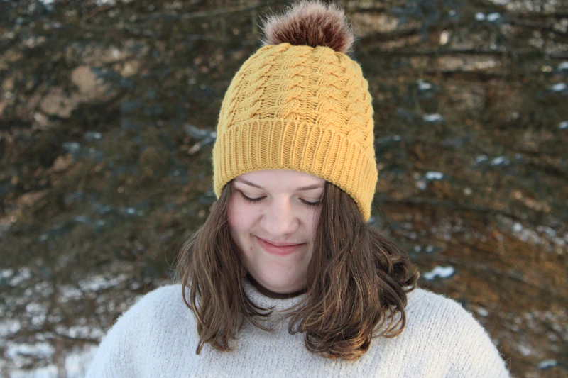 Kobieta w ciepłym swetrze i żółtej czapce