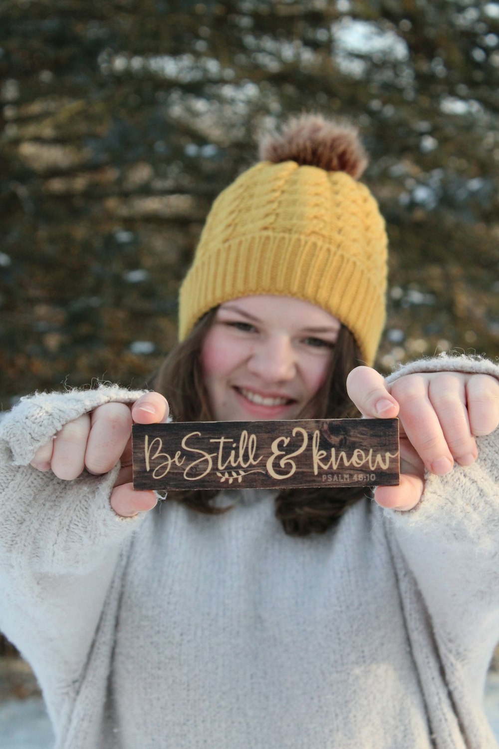 woman in yellow knit cap holding black wooden board