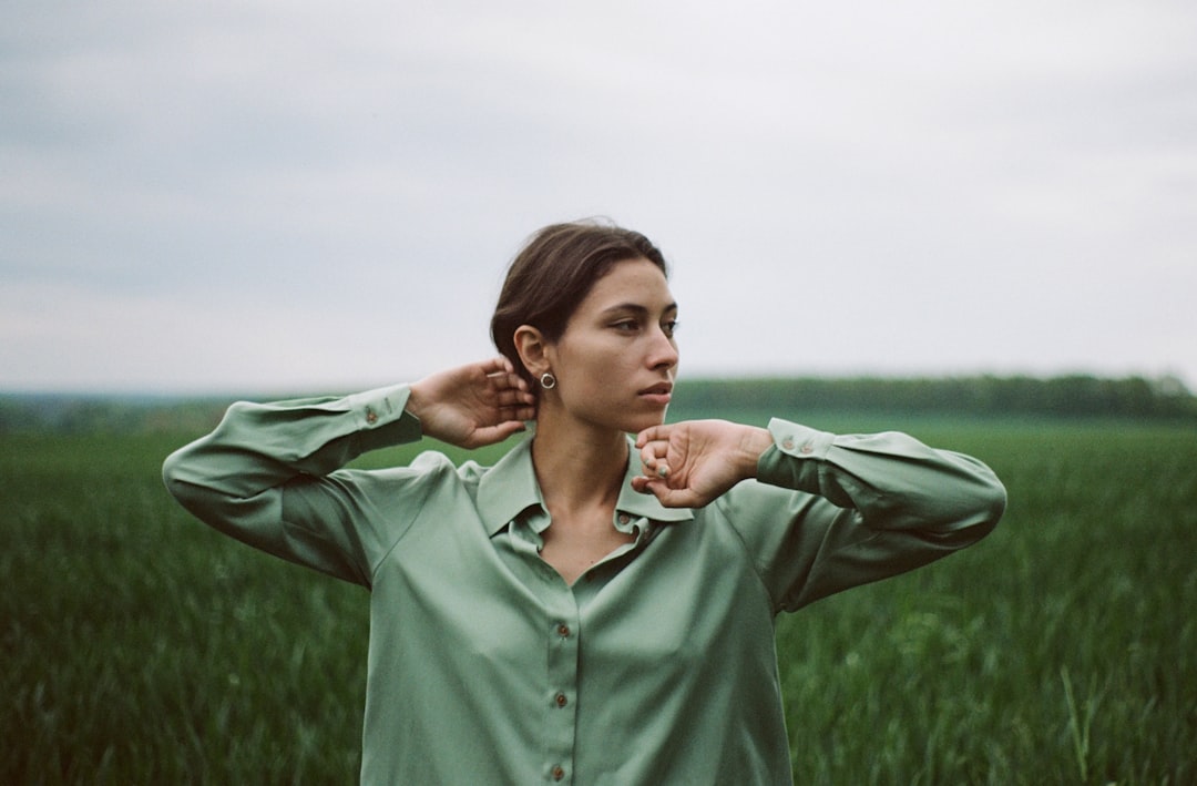 woman in green button up long sleeve shirt standing on green grass field during daytime