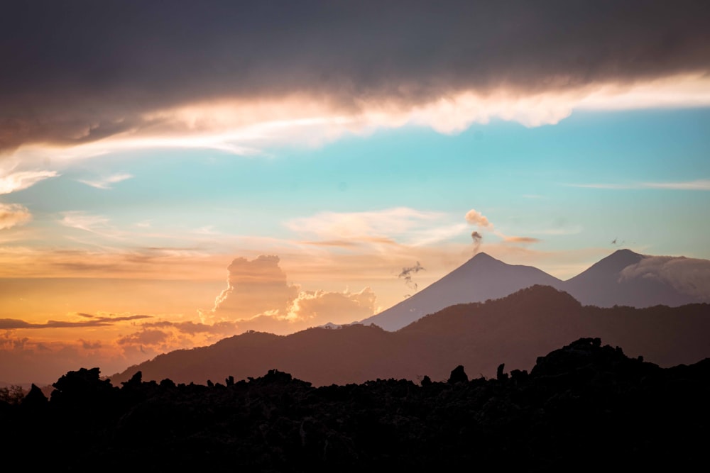 silhouette of mountain under cloudy sky during sunset