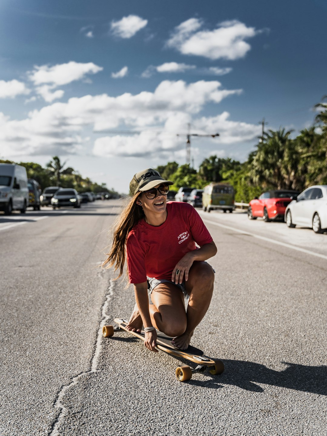 woman in red crew neck t-shirt and brown shorts sitting on gray asphalt road during