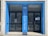 The entrance features two black glass doors framed by a blue facade. Text in white on the blue background reads 'Bibliothèque Quentin Blake' and 'Institut Français'. There are notices posted on the glass doors, and reflections can be seen in the glass.