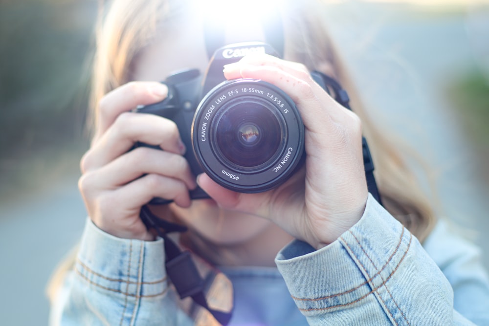 man in blue and white plaid dress shirt holding black nikon dslr camera