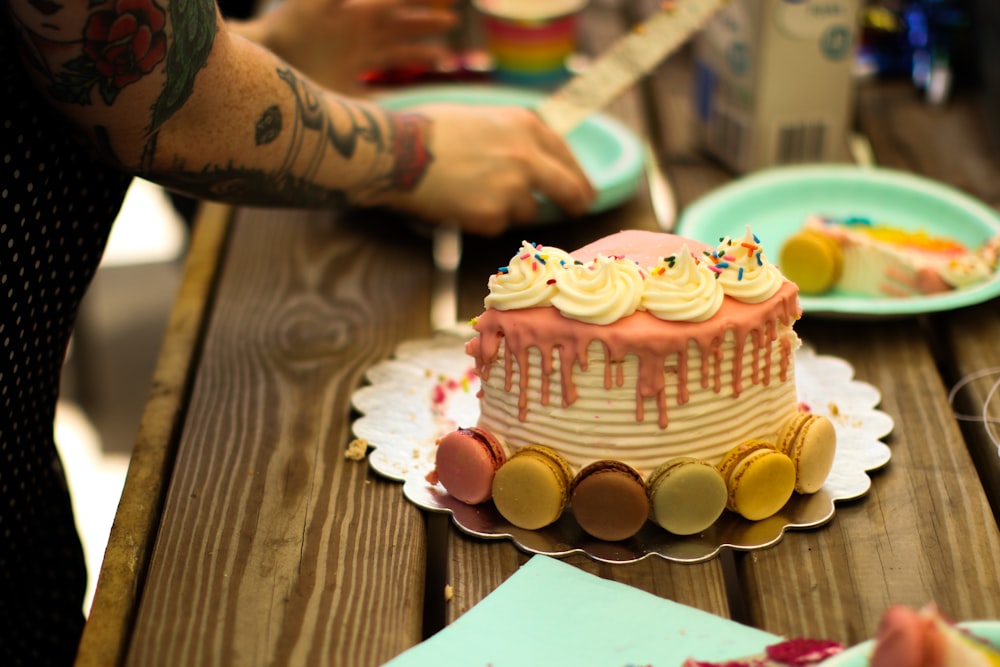 person holding white and pink cupcake