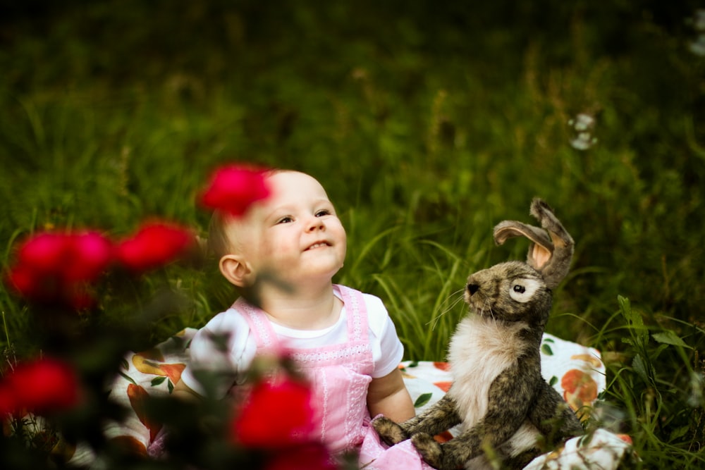 girl in pink shirt sitting on brown log with birds on her lap