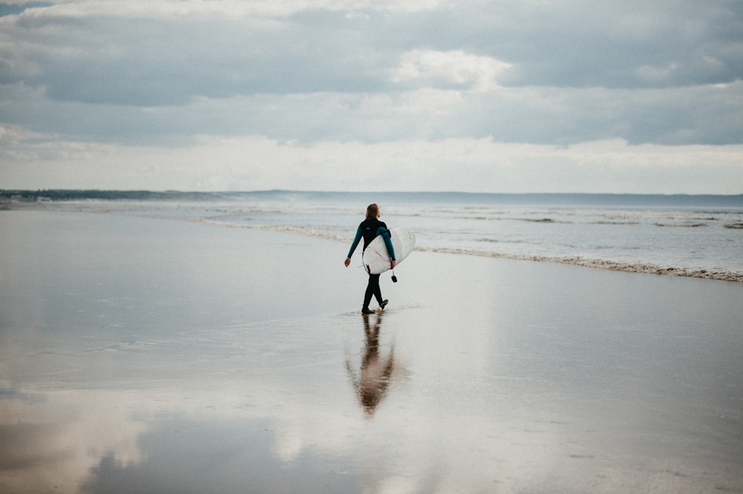 woman in black tank top and black pants walking on beach during daytime