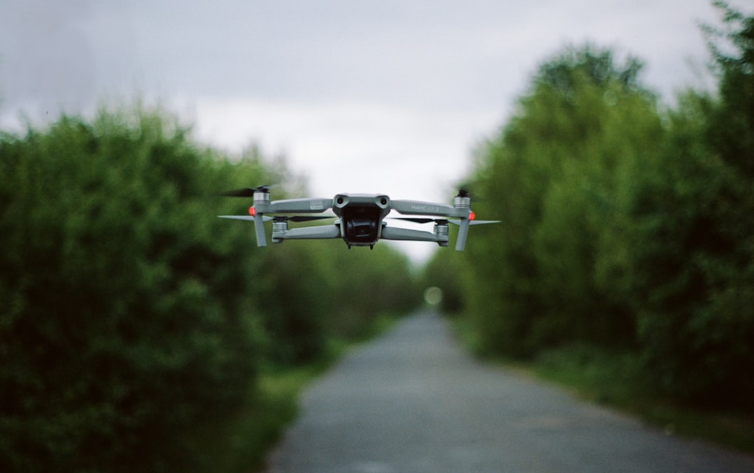 white and black drone flying over the road during daytime