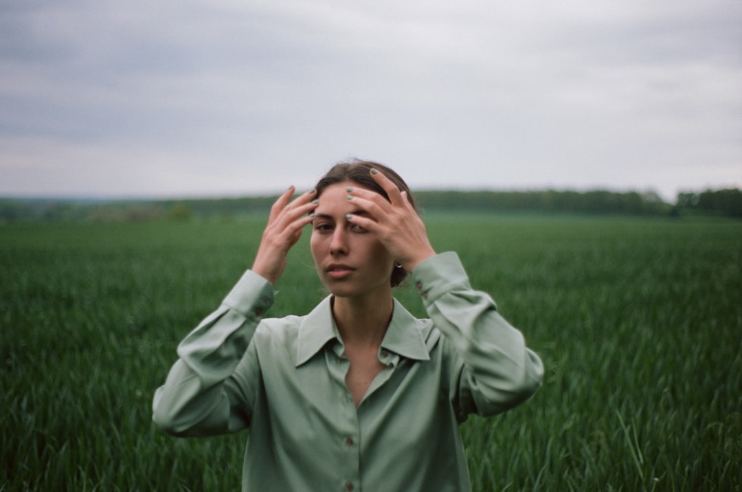 man in green dress shirt covering face with his hands