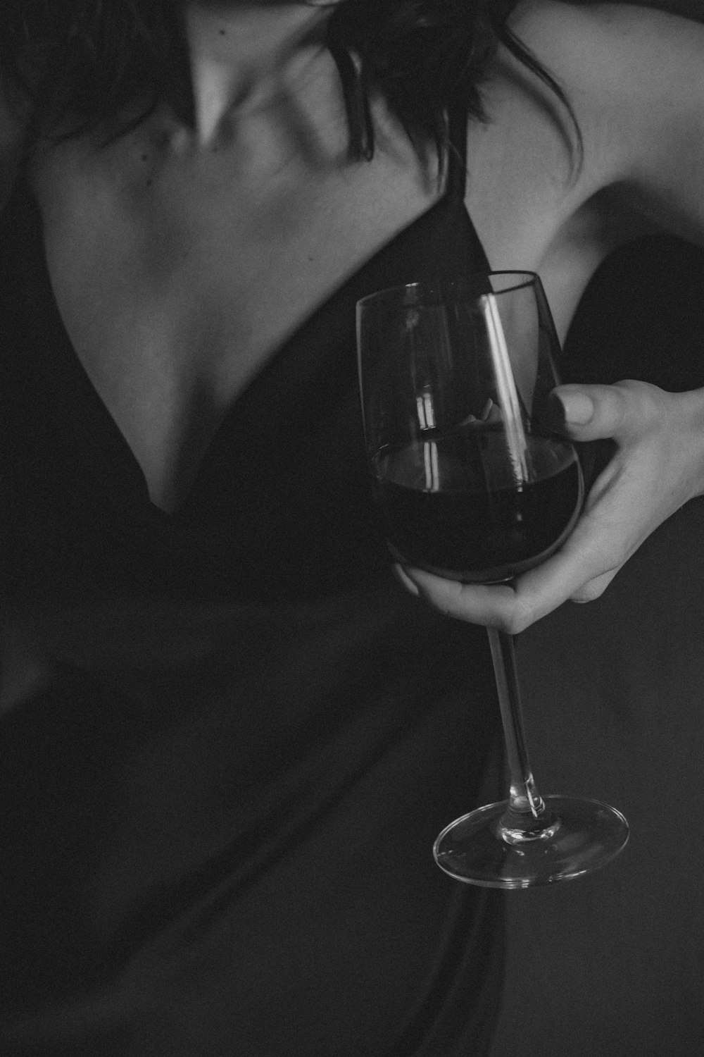 foto em tons de cinza da mulher que segura o copo de vinho
