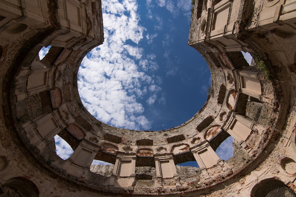 vue de l’œil de vers d’un bâtiment en béton brun sous un ciel nuageux ensoleillé bleu et blanc pendant