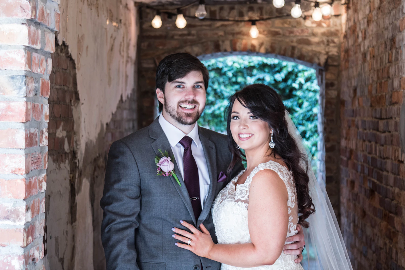 Man in formal black suit jacket beside woman in elegant white wedding dress during outdoor portrait session