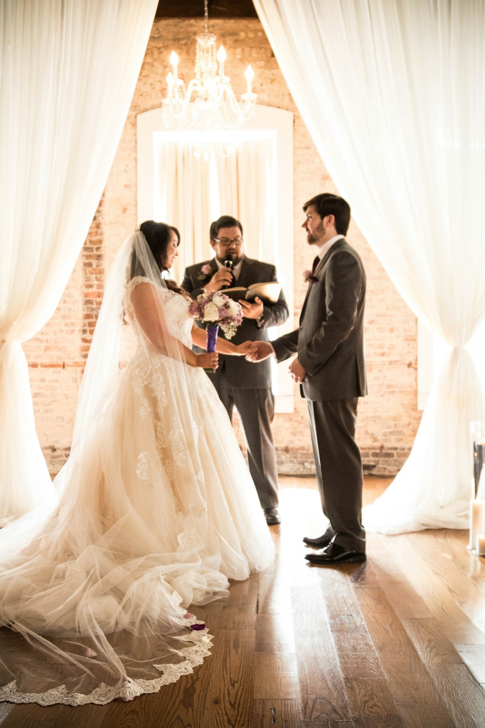 man and woman in wedding dress standing beside white curtain