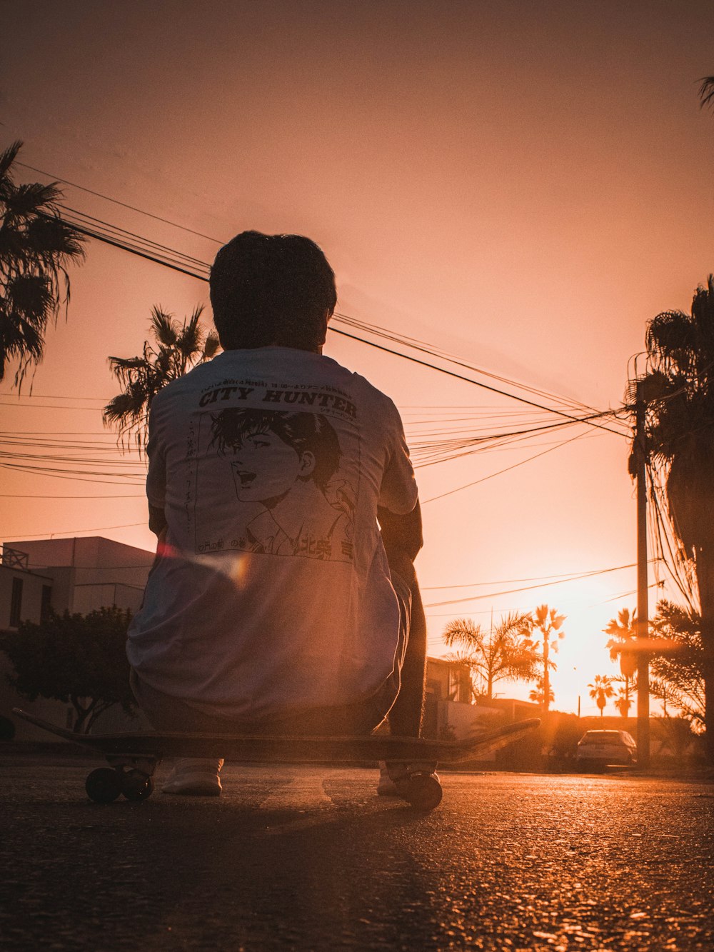 man in white shirt sitting on brown wooden bench during sunset