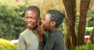 smiling woman in gray long sleeve shirt carrying boy in white and black striped shirt during