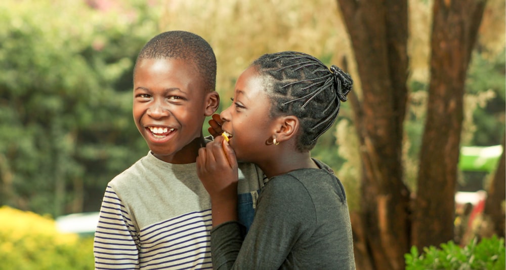 smiling woman in gray long sleeve shirt carrying boy in white and black striped shirt during