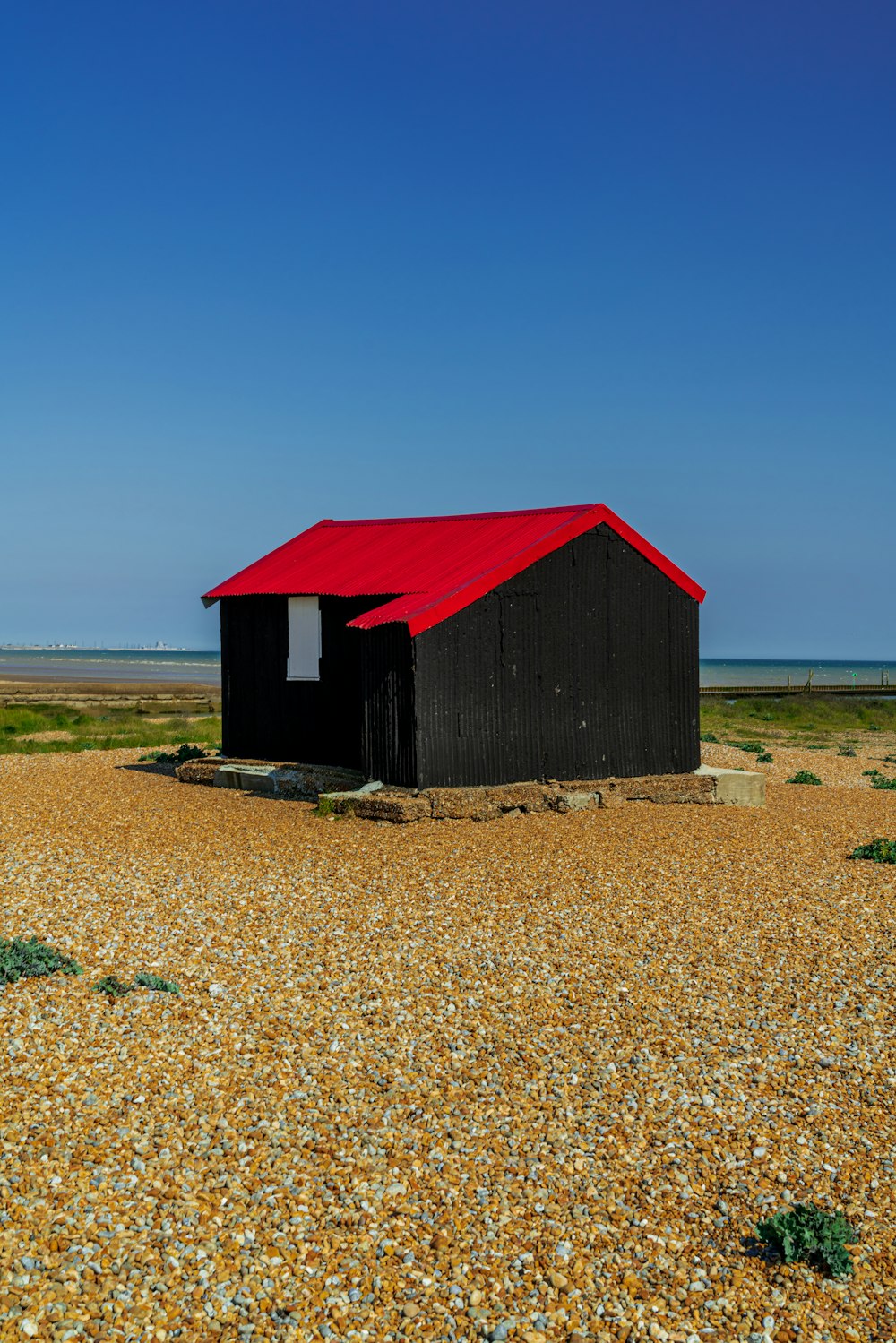 maison en bois rouge sur un champ brun sous un ciel bleu pendant la journée