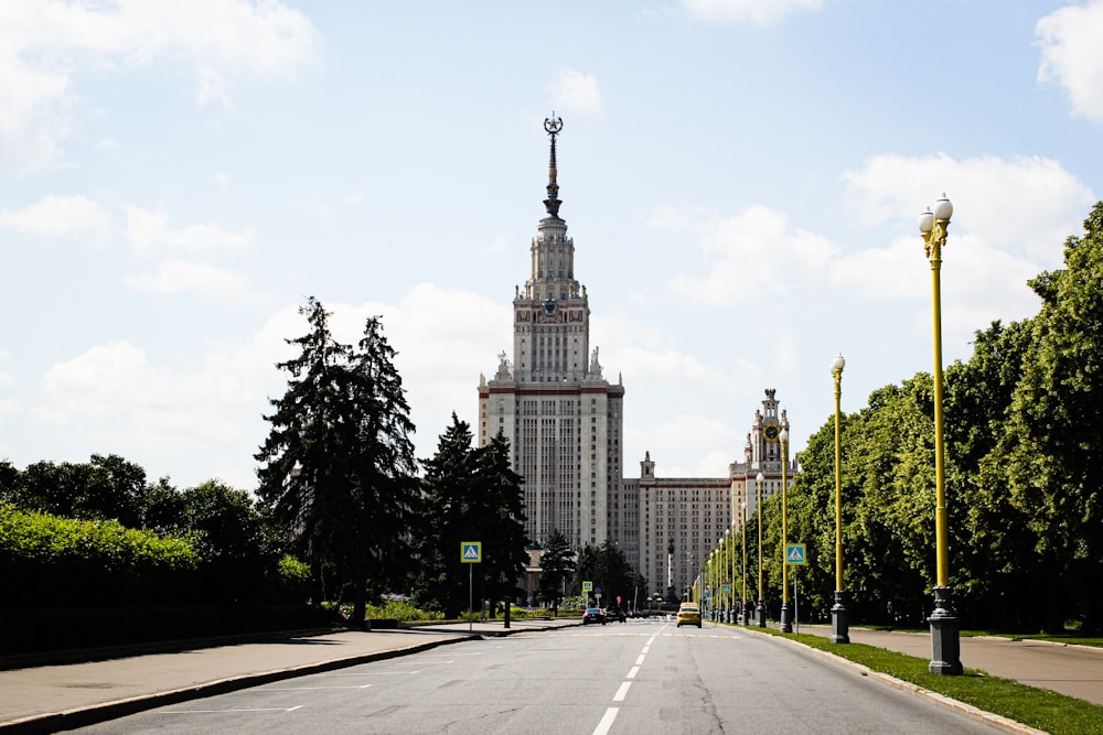 gray concrete road between green trees and high rise buildings during daytime