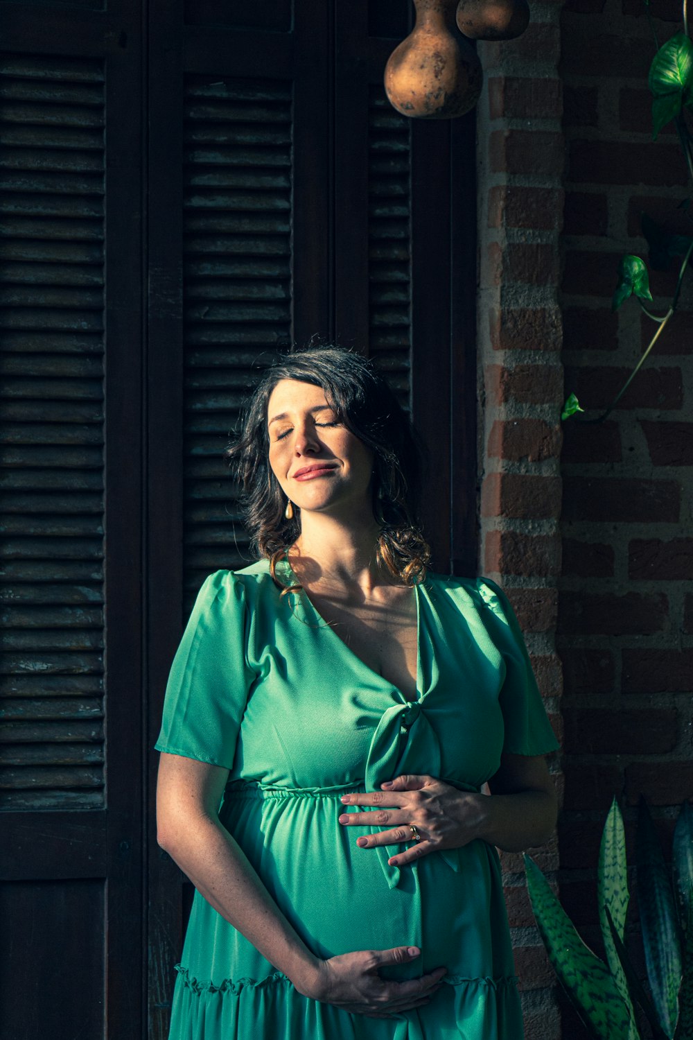 woman in green v neck shirt and black cardigan standing beside black wooden wall