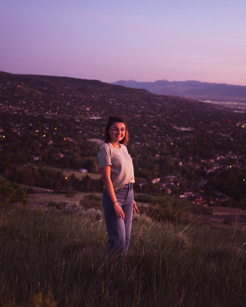 woman in white t-shirt standing on green grass field during daytime