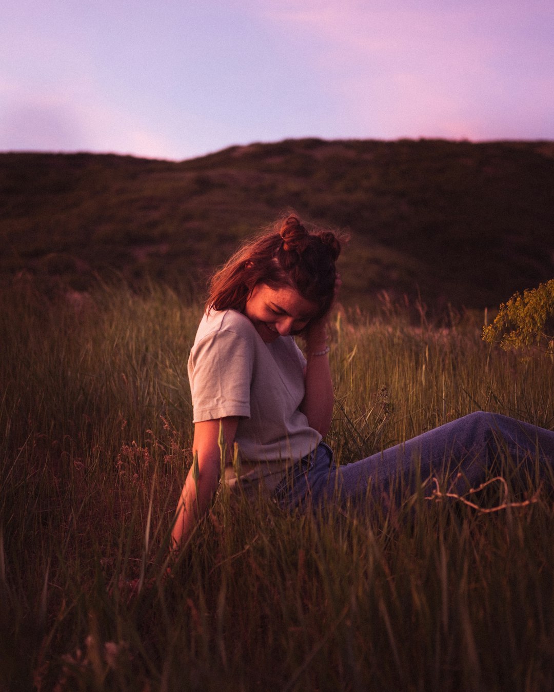 woman in gray shirt sitting on brown grass field