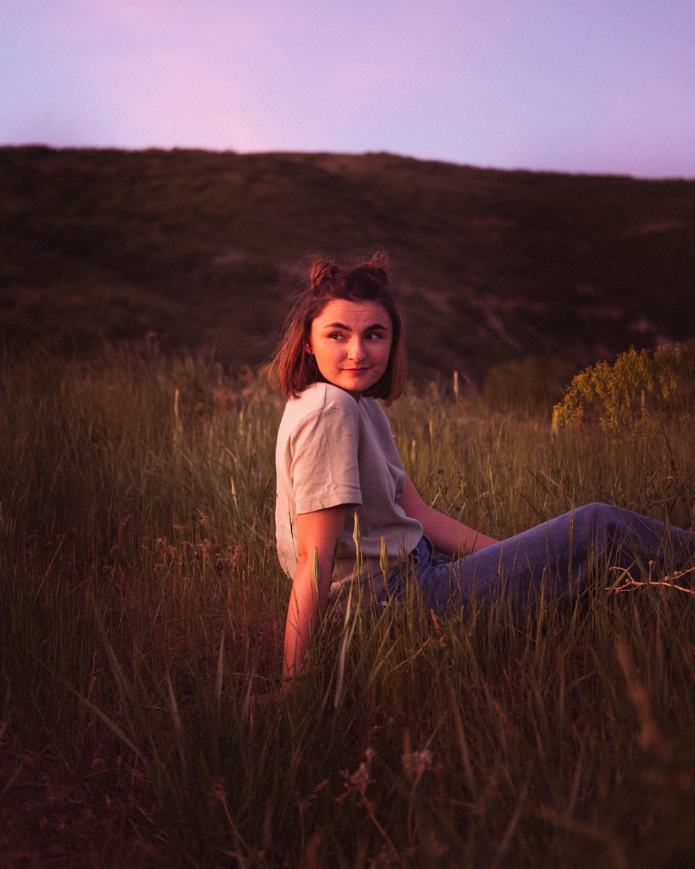 woman in white shirt sitting on brown grass field during daytime