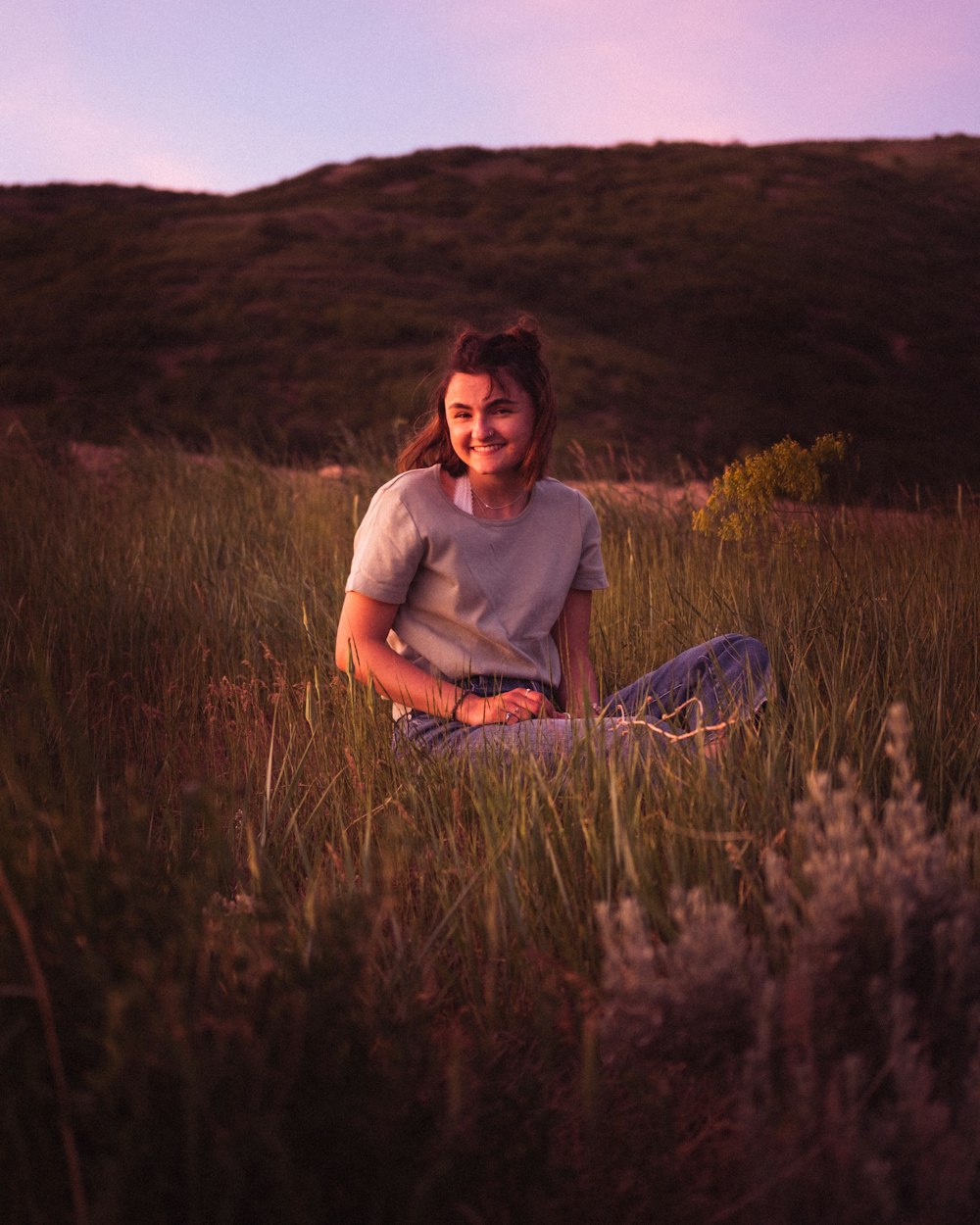 man in gray crew neck t-shirt sitting on green grass field during daytime