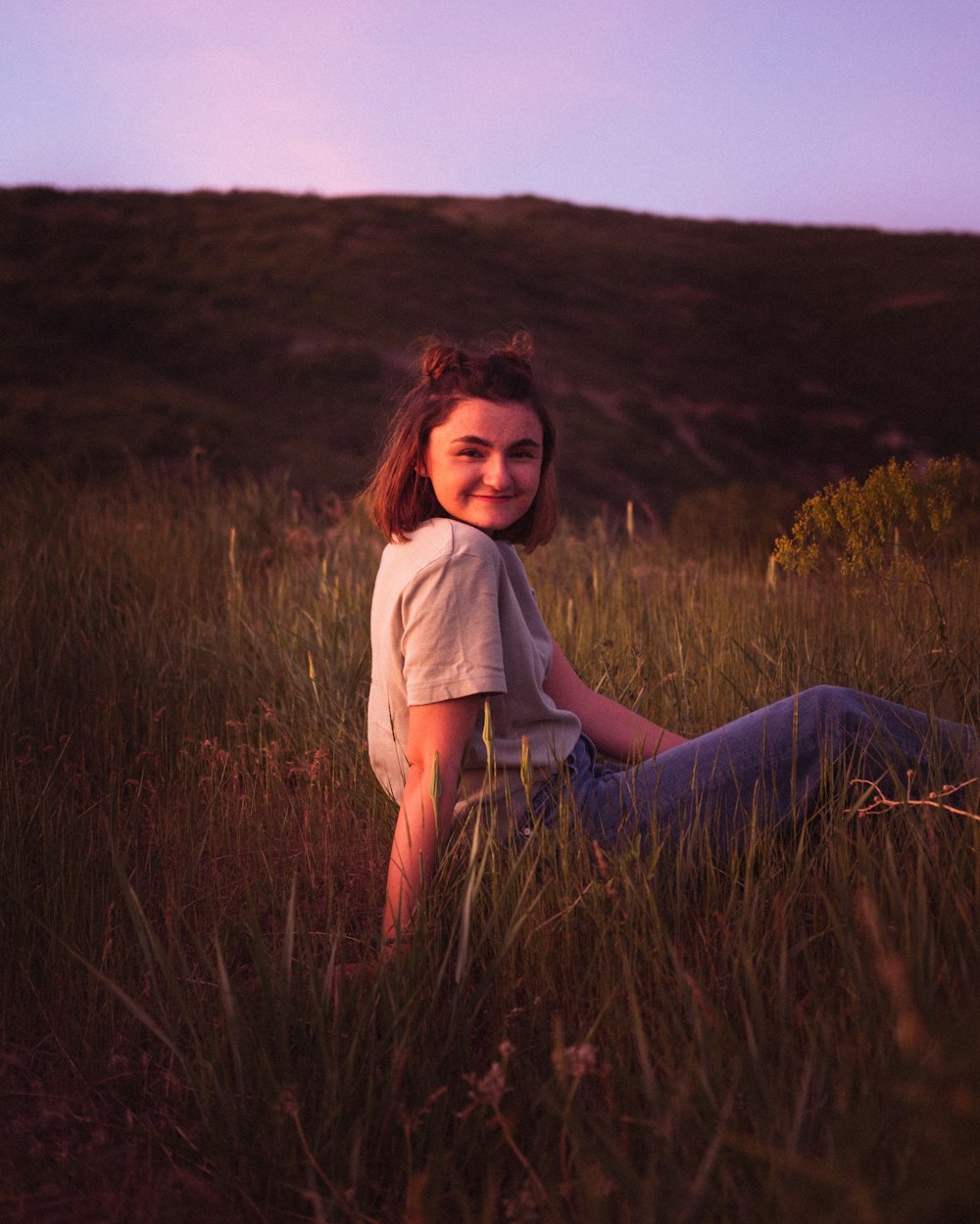 woman in white shirt sitting on grass field