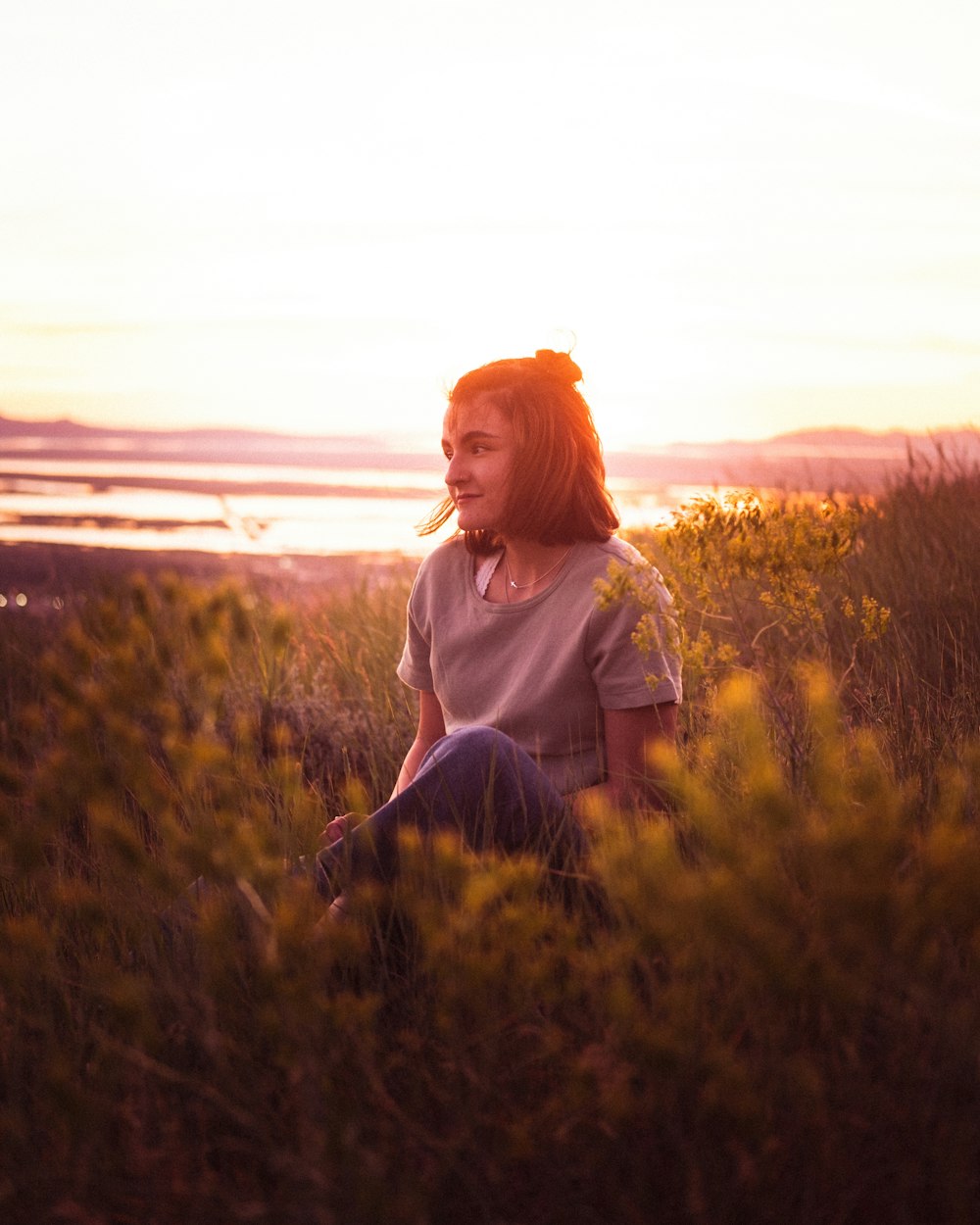 woman in purple coat standing on green grass field during sunset