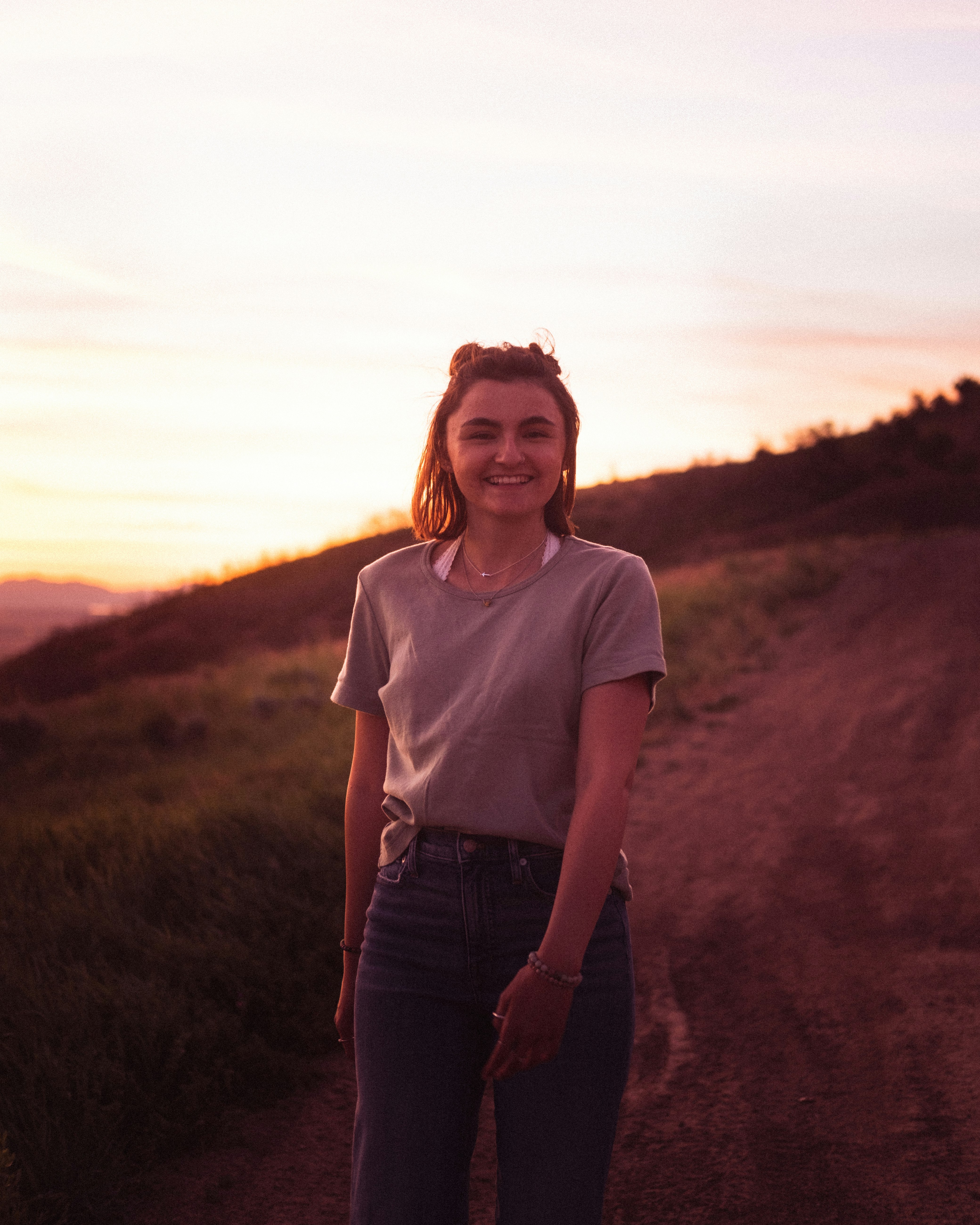 woman in white crew neck t-shirt standing on brown grass field during daytime