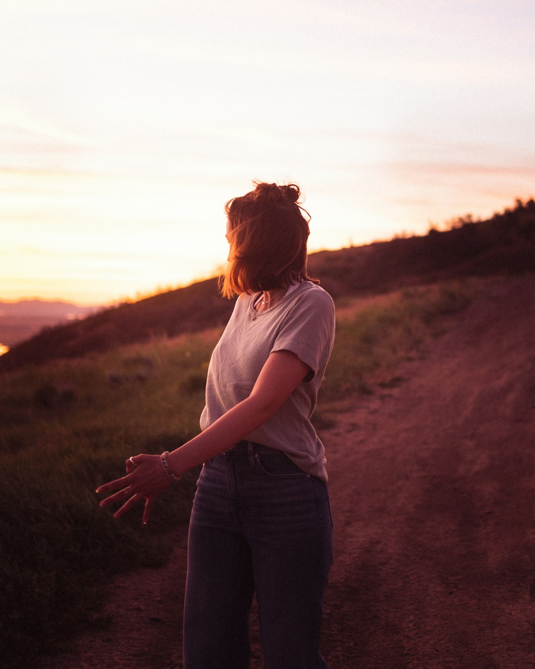 woman in white t-shirt and black pants standing on brown field during daytime