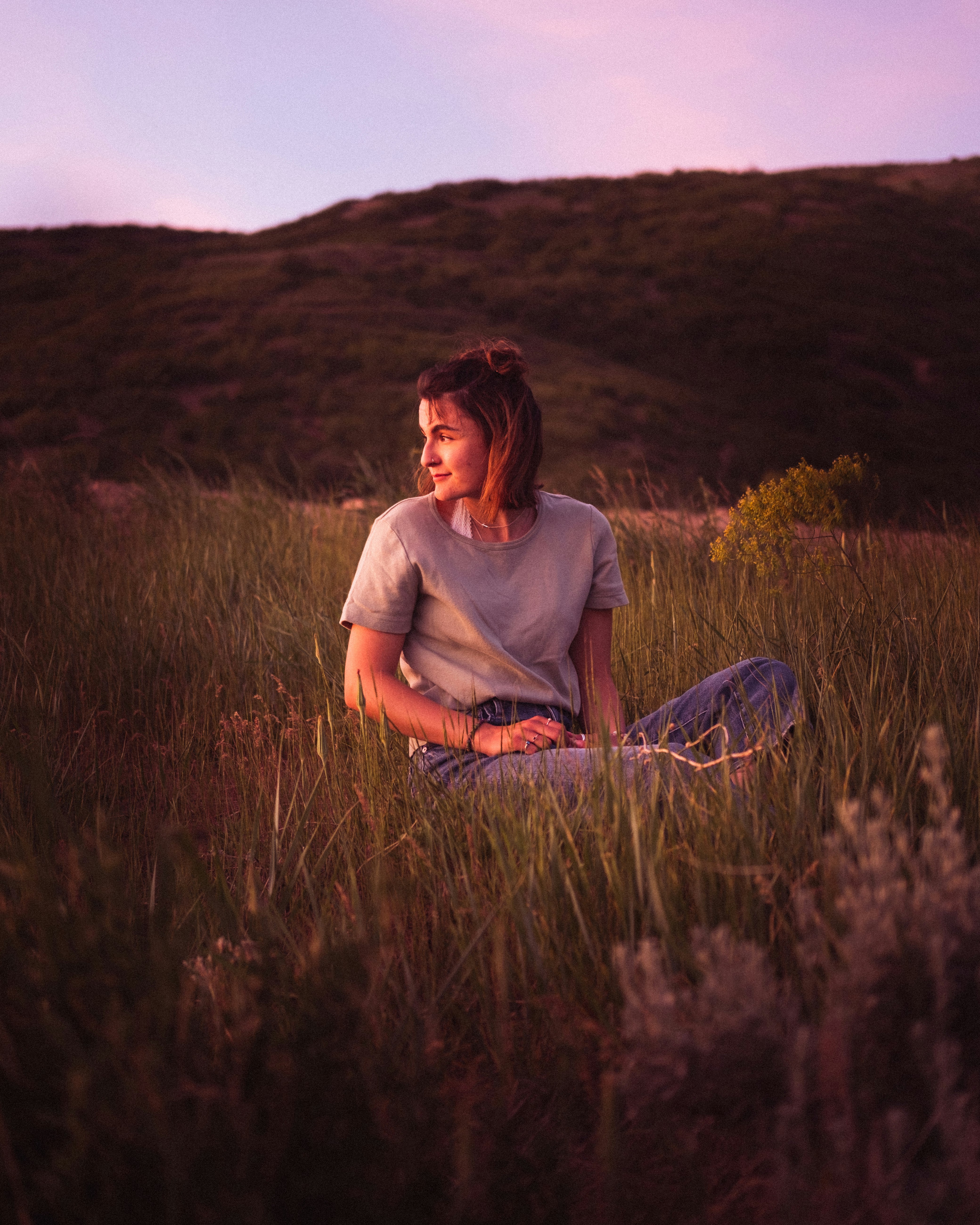 woman in gray crew neck t-shirt sitting on green grass field during daytime