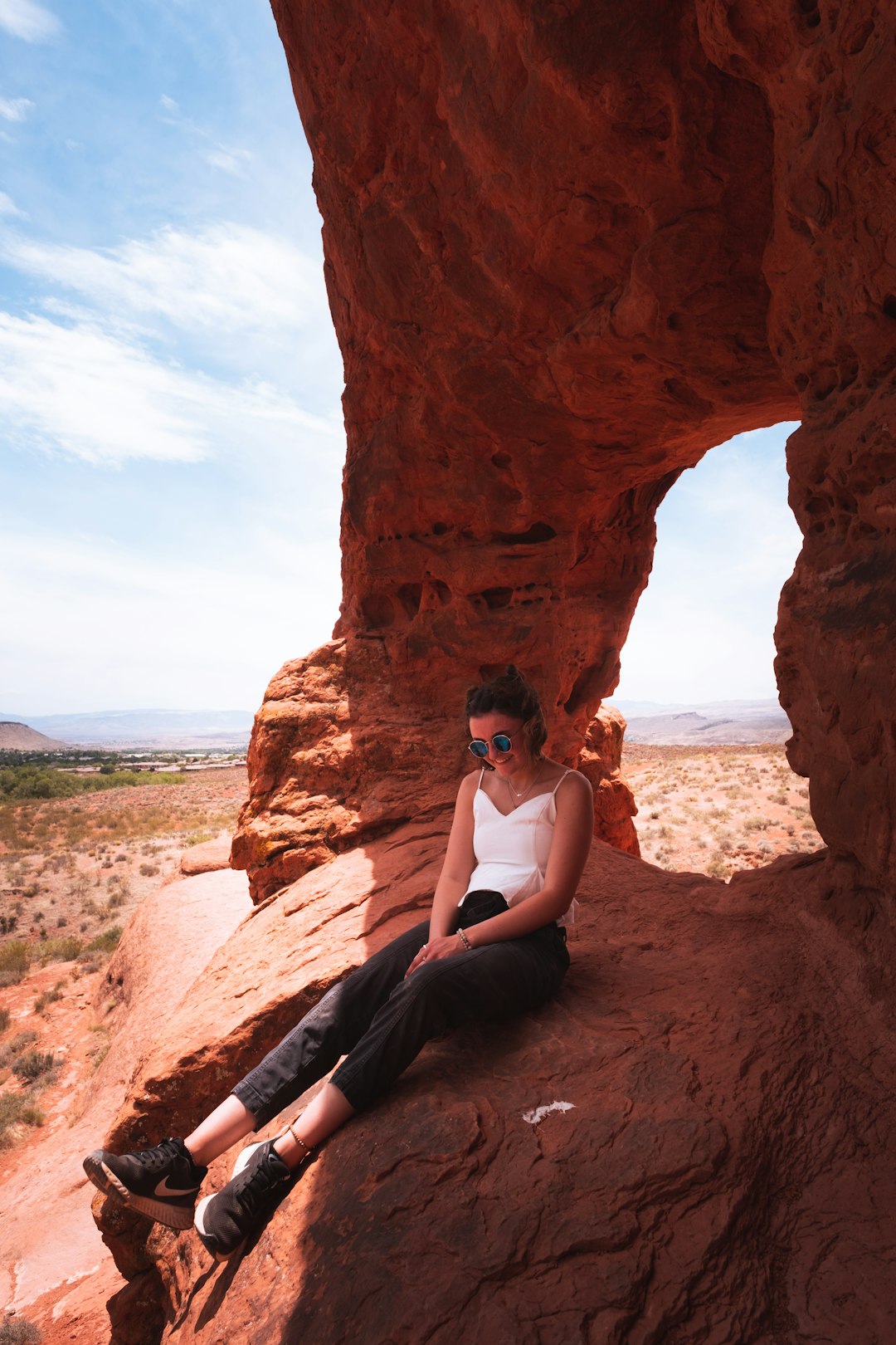 woman in white tank top sitting on brown rock formation during daytime