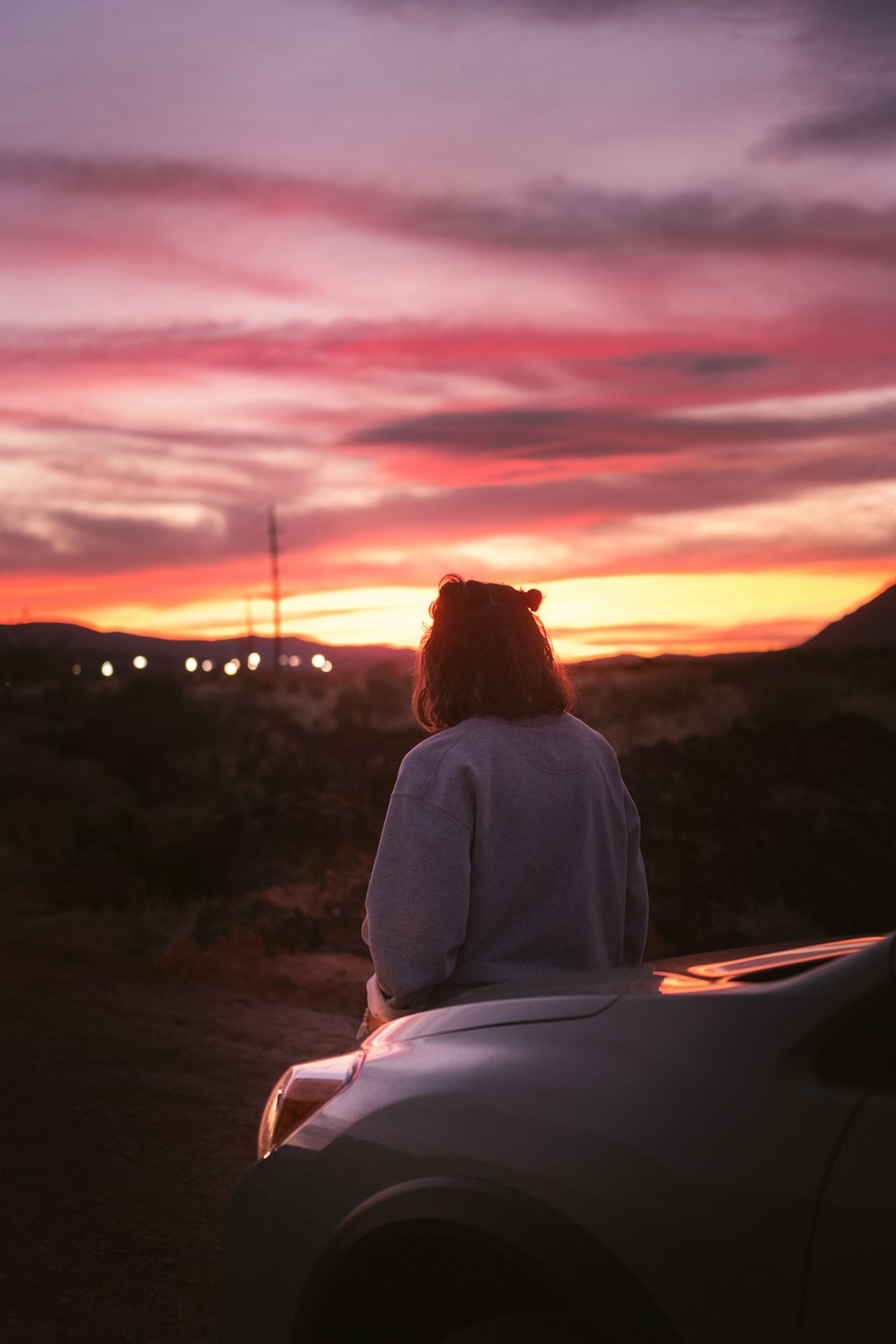 woman in white long sleeve shirt sitting on rock during sunset